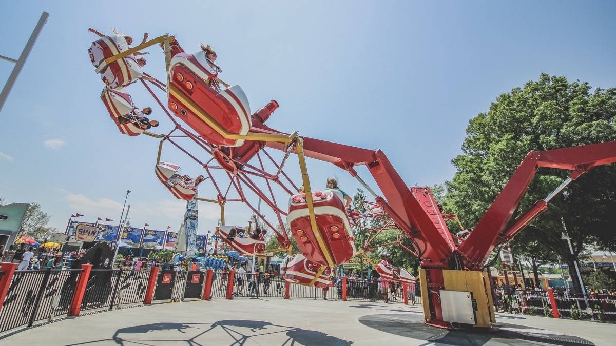 Red amusement park ride at Carowinds with a theme park setting in the background under a blue sky